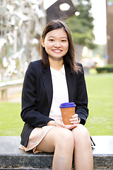 Image showing Young female Asian executive drinking coffee