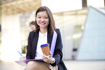 Image showing Young female Asian business executive holding file