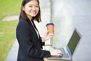 Image showing Young Asian female business executive using laptop