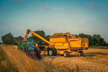 Image showing Harvester loading grain on a truck