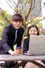 Image showing Young Asian female and male business executive using laptop