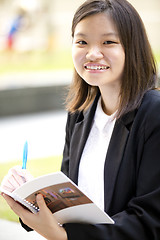 Image showing Young Asian female business executive writing on notepad