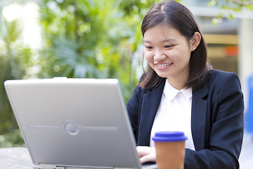 Image showing Young Asian female business executive using laptop