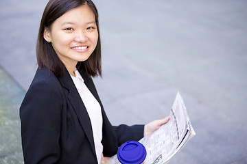 Image showing Young Asian female business executive reading newspaper