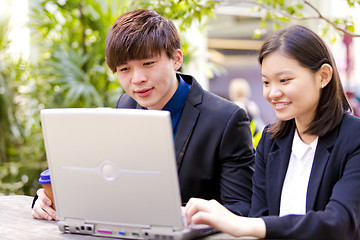 Image showing Young Asian female and male business executive using laptop