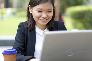 Image showing Young Asian female business executive using laptop