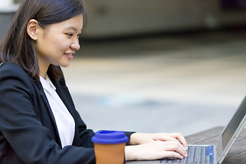 Image showing Young Asian female business executive using laptop