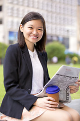 Image showing Young Asian female business executive reading newspaper