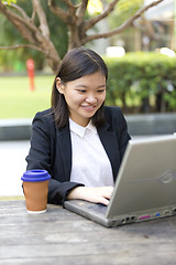 Image showing Young Asian female business executive using laptop