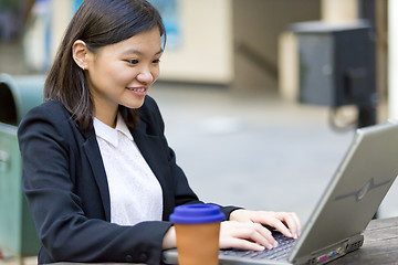 Image showing Young Asian female business executive using laptop