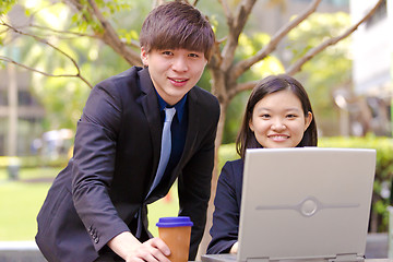 Image showing Young Asian female and male business executive using laptop