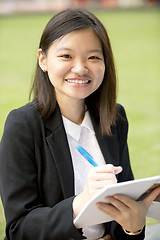 Image showing Young Asian female business executive writing on notepad