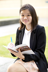 Image showing Young Asian female business executive writing on notepad