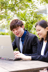 Image showing Young Asian female and male business executive using laptop