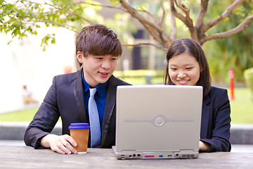 Image showing Young Asian female and male business executive using laptop