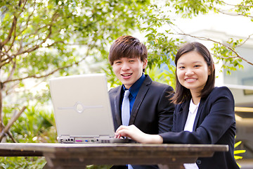 Image showing Young Asian female and male business executive using laptop