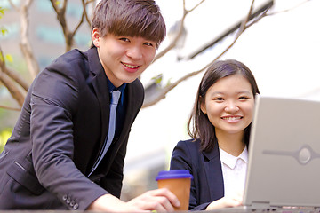 Image showing Young Asian female and male business executive using laptop