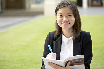 Image showing Young Asian female business executive writing on notepad