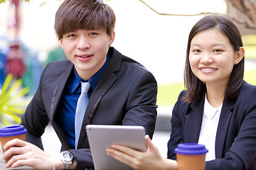 Image showing Young Asian female and male business executive using tablet