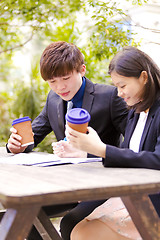 Image showing Young Asian female and male business executive reading newspaper