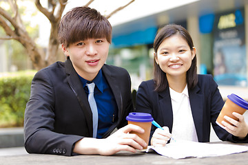 Image showing Young Asian female and male business executive reading newspaper