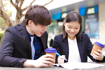 Image showing Young Asian female and male business executive reading newspaper