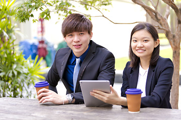 Image showing Young Asian female and male business executive using tablet