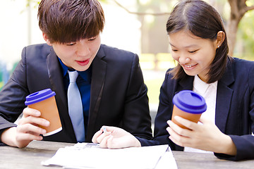 Image showing Young Asian female and male business executive reading newspaper