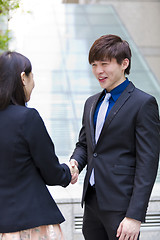 Image showing Young Asian female and male business executive shaking hands