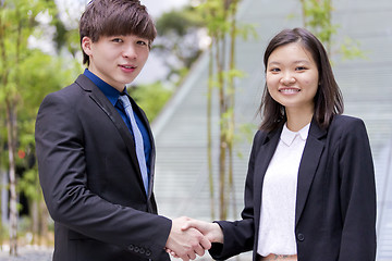 Image showing Young Asian female and male business executive shaking hands