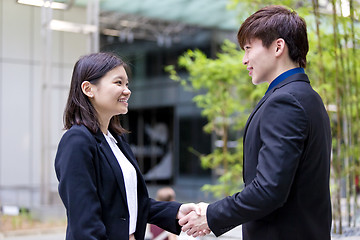 Image showing Young Asian female and male business executive shaking hands