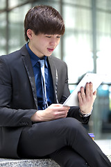 Image showing Young Asian male business executive using table