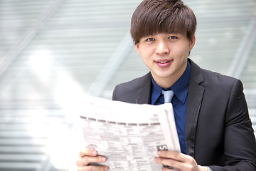 Image showing Young Asian business executive reading newspaper