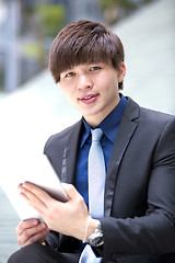 Image showing Young Asian male business executive using tablet