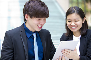 Image showing Young Asian female and male business executive using tablet