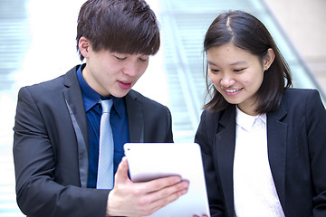 Image showing Young Asian female and male business executive using tablet