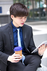 Image showing Young Asian male business executive using tablet