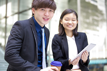 Image showing Young Asian female and male business executive using tablet