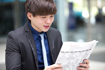 Image showing Young Asian male business executive reading newspaper