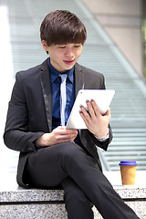 Image showing Young Asian male business executive using tablet