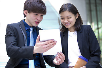 Image showing Young Asian female and male business executive using tablet