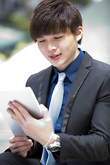 Image showing Young Asian male business executive using tablet