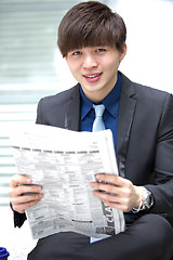 Image showing Young Asian male business executive reading newspaper