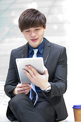 Image showing Young Asian male business executive using tablet