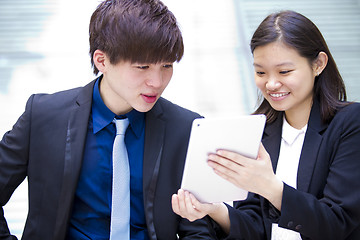 Image showing Young Asian female and male business executive using tablet