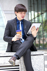 Image showing Young Asian male business executive using tablet