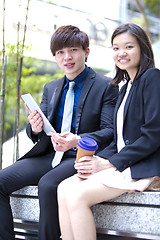 Image showing Young Asian female and male business executive using tablet