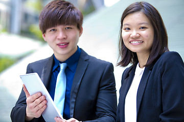 Image showing Young Asian female and male business executive using tablet