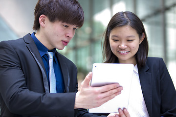 Image showing Young Asian female and male business executive using tablet