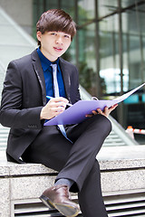 Image showing Young Asian business executive in suit holding file